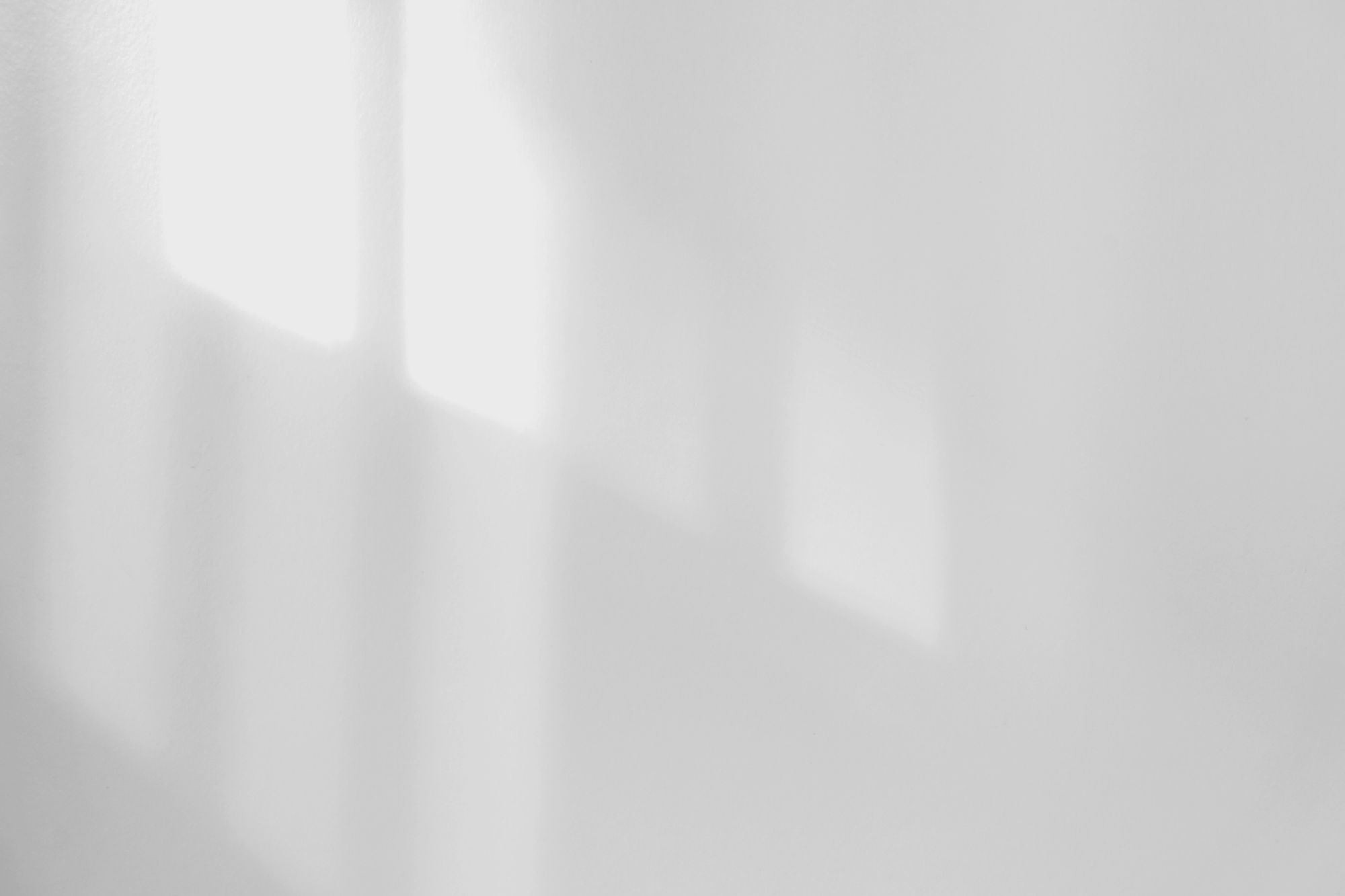 Soft architectural shadows across a pale wall